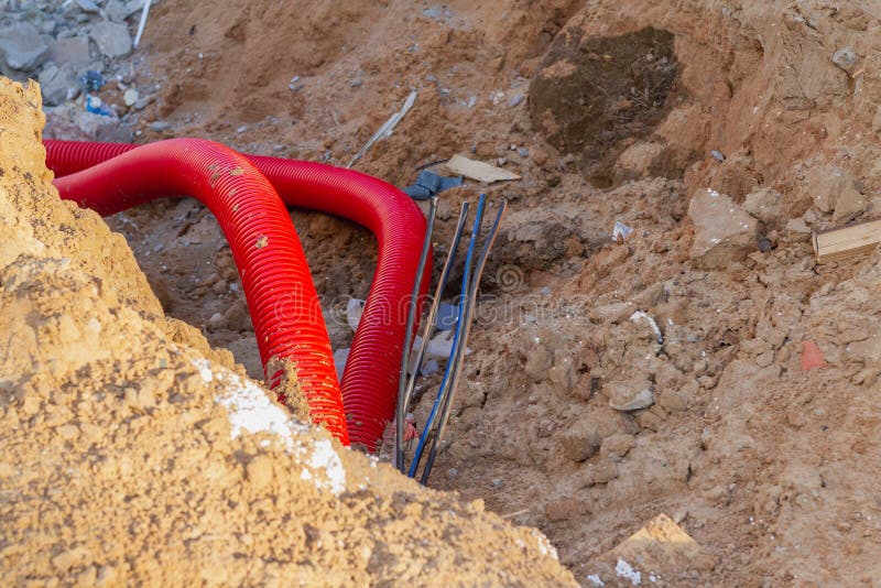 Laying an Insulating Plastic Pipe with an Electric Cable Underground during the Construction of