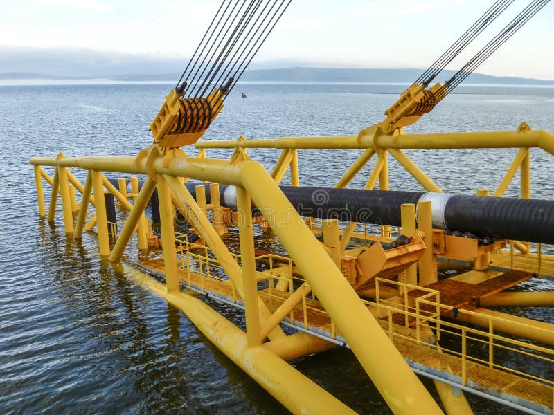 Laying of pipes with pipe-laying barge crane near the shore. Descent of the pipeline to a bottom exhausting with the pipelaying b royalty free stock image Laying of pipes with pipe-laying barge crane near the shore. Descent of the pipeline to a bottom exhausting with the pipelaying b royalty free stock image
