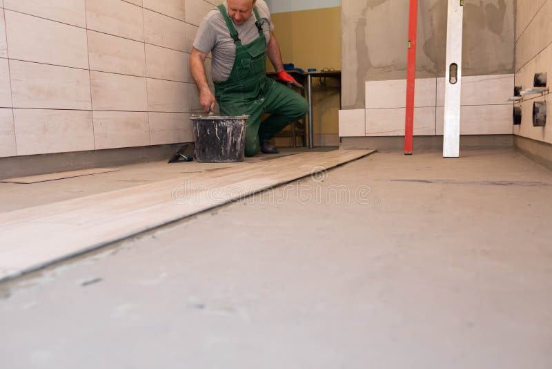 Free Photo  Builder checks the quality of the laid tiles with a manual  bubble level construction worker installing ceramic floor tiles on  construction sites floor repair selective focus