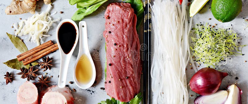 Layout of products on Vietnamese Pho Bo soup on gray background. Traditional Vietnamese Pho bo soup with herbs, meat, rice noodles, broth.