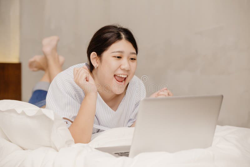 Lazy girl teen happy exciting good news from computer laptop lay on bed working at home
