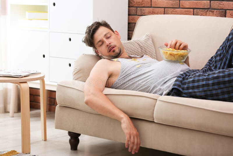 Lazy man with bowl of chips sleeping on sofa