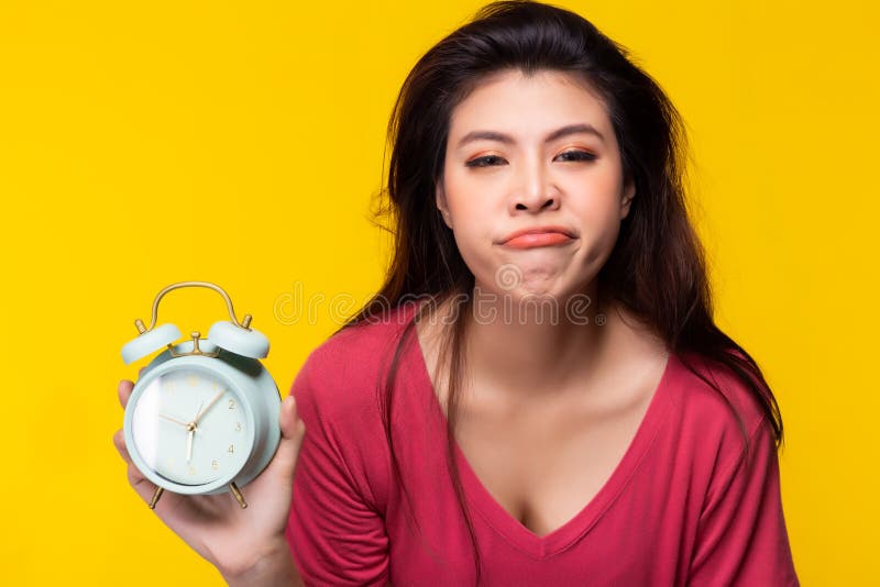 Lazy Woman Make Expressive Face And Grimace Face In Monday Morning By Holding Alarm Clock Sleepy