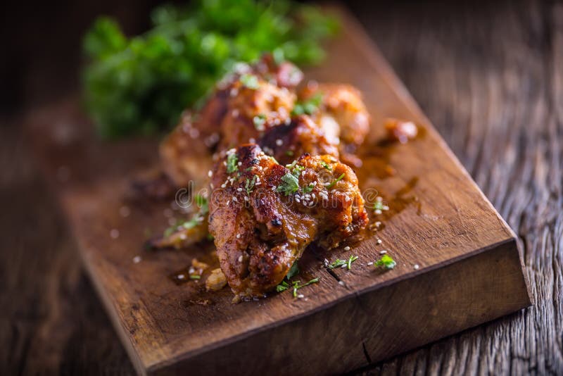 Le ali di pollo hanno grigliato l'erba ed il sesamo del prezzemolo del BBQ sul bordo di legno immagine stock libera da diritti Le ali di pollo hanno grigliato l'erba ed il sesamo del prezzemolo del BBQ sul bordo di legno immagine stock libera da diritti