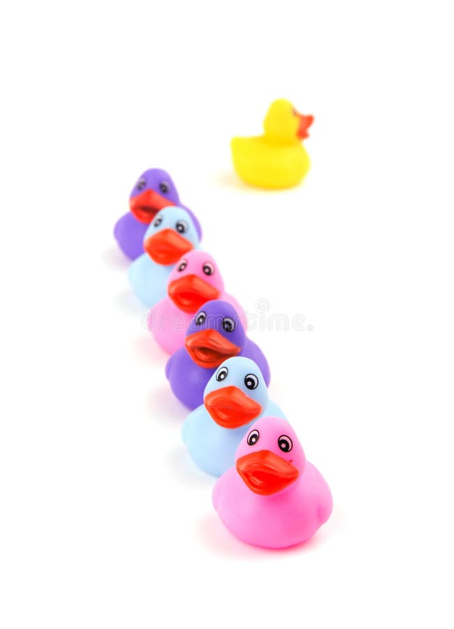 Rubber ducks in a row, with one headed to opposite direction, fading away - concept of individuality; focus on front pink duck. Rubber ducks in a row, with one headed to opposite direction, fading away - concept of individuality; focus on front pink duck