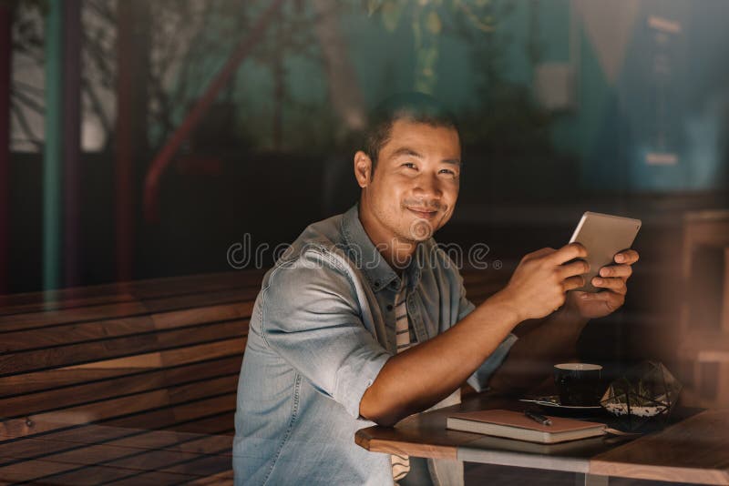 Le asiatiskt bläddra för man som är online-, medan sitta i ett kafé royaltyfri fotografi Le asiatiskt bläddra för man som är online-, medan sitta i ett kafé royaltyfri fotografi