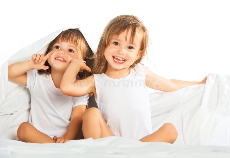 Le bambine felici gemella la sorella a letto nell'ambito dell'avere generale fotografie stock libere da diritti