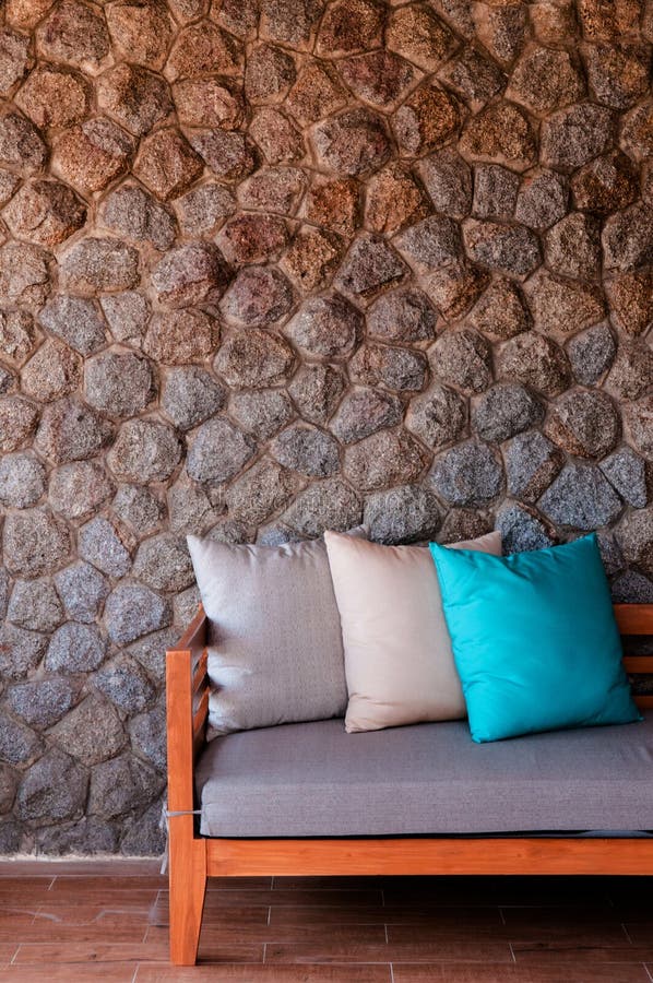 Le banc en bois avec le siège et l'oreiller de tissu a mis contre le mur en pierre photo stock Le banc en bois avec le siège et l'oreiller de tissu a mis contre le mur en pierre photo stock