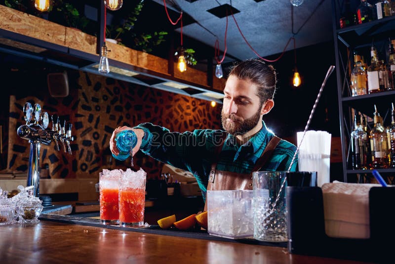 Le barman avec une barbe fait le cocktail à la barre photographie stock Le barman avec une barbe fait le cocktail à la barre photographie stock