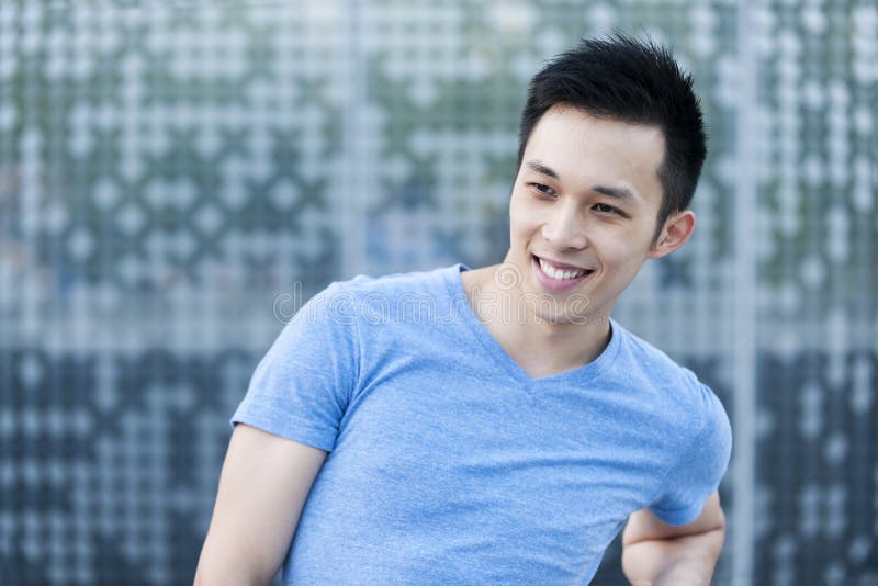 Portrait of confident young asian man smiling in urban environment with copy space. Portrait of confident young asian man smiling in urban environment with copy space
