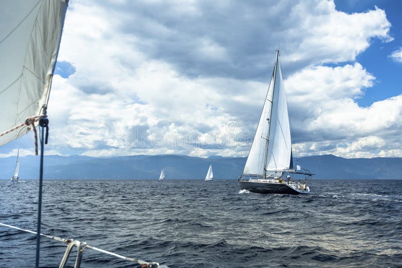 Le bateau de navigation fait de la navigation de plaisance avec les voiles blanches en mer par temps orageux nature image libre de droits Le bateau de navigation fait de la navigation de plaisance avec les voiles blanches en mer par temps orageux nature image libre de droits