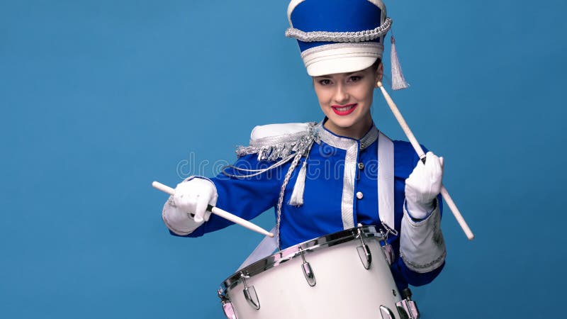 Le batteur gay de charme dans un uniforme bleu chante et joue du tambour.