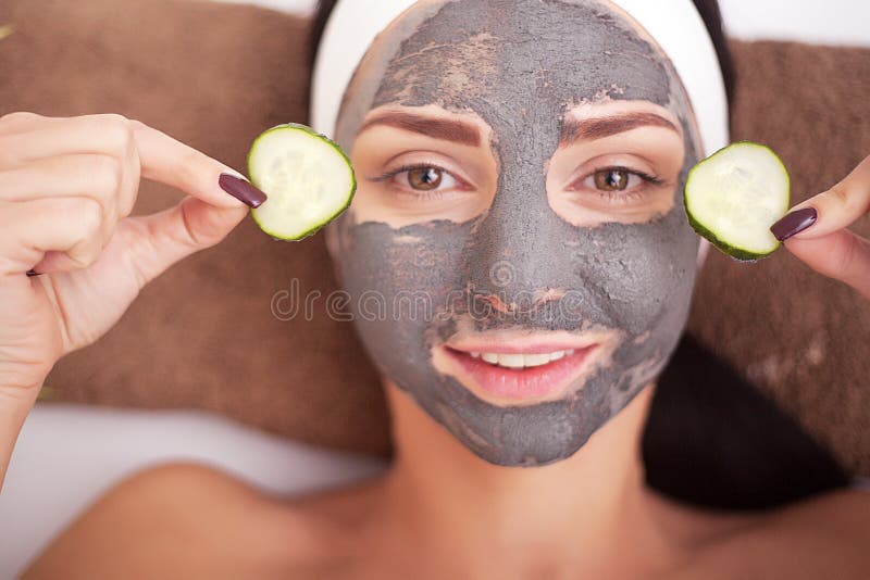 Le beau femme ayant le masque facial d'argile s'appliquent par le beautician photo libre de droits Le beau femme ayant le masque facial d'argile s'appliquent par le beautician photo libre de droits