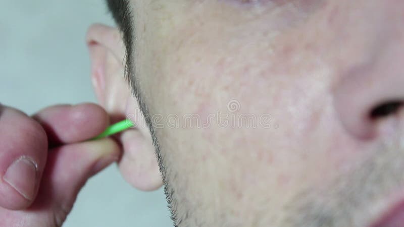 Le beau jeune homme nettoie son oreille avec un bâton d'oreille.