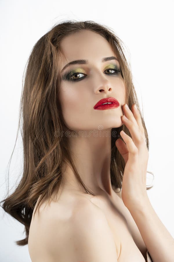 Le beau modèle de fille avec les lèvres rouges préparent et des sourires nus d'épaules et touchent sensuel le visage avec ses doi photographie stock Le beau modèle de fille avec les lèvres rouges préparent et des sourires nus d'épaules et touchent sensuel le visage avec ses doi photographie stock