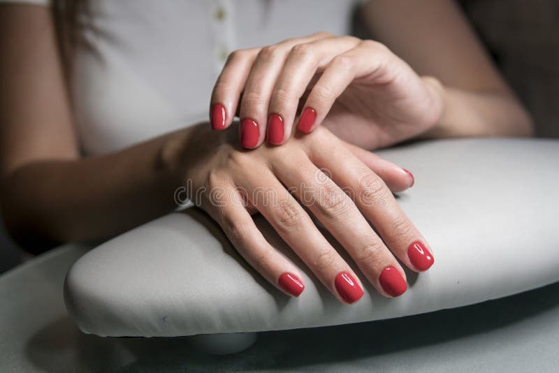 Beautiful female hands with red nails in beauty nail salon. Beautiful female nails and manicure. Beautiful female hands with red nails in beauty nail salon. Beautiful female nails and manicure