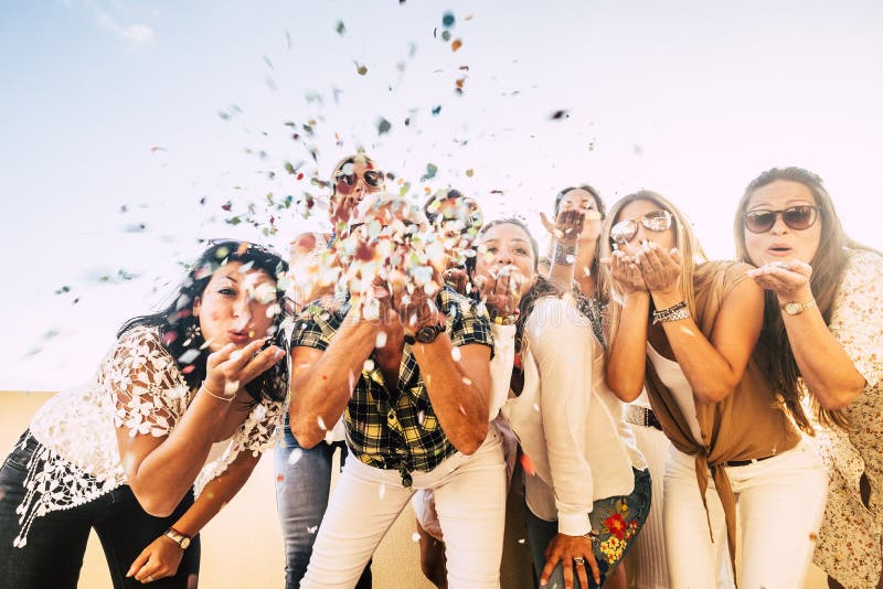 Le bonheur et le concept joyeux - un groupe de femmes heureuses que les gens célèbrent tout ensemble soufflant des confettis et s image libre de droits