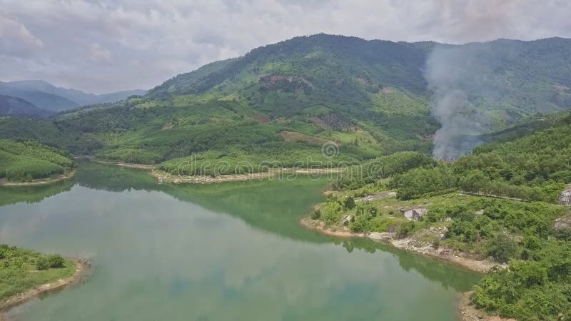 Le bourdon approche les collines vertes derrière le lac avec le feu commandé