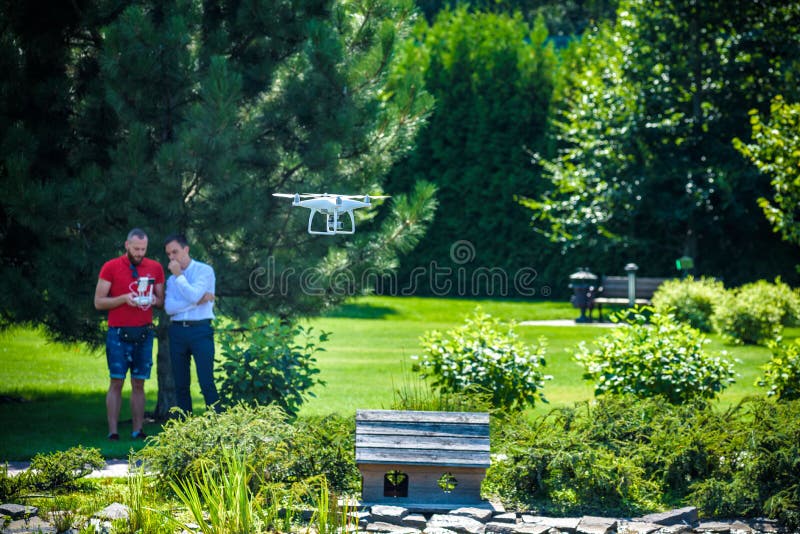 Le bourdon compact plane devant deux hommes de hippie L'hélicoptère de quadruple vole près du pilote Innov l'explorant de récolte photos libres de droits Le bourdon compact plane devant deux hommes de hippie L'hélicoptère de quadruple vole près du pilote Innov l'explorant de récolte photos libres de droits
