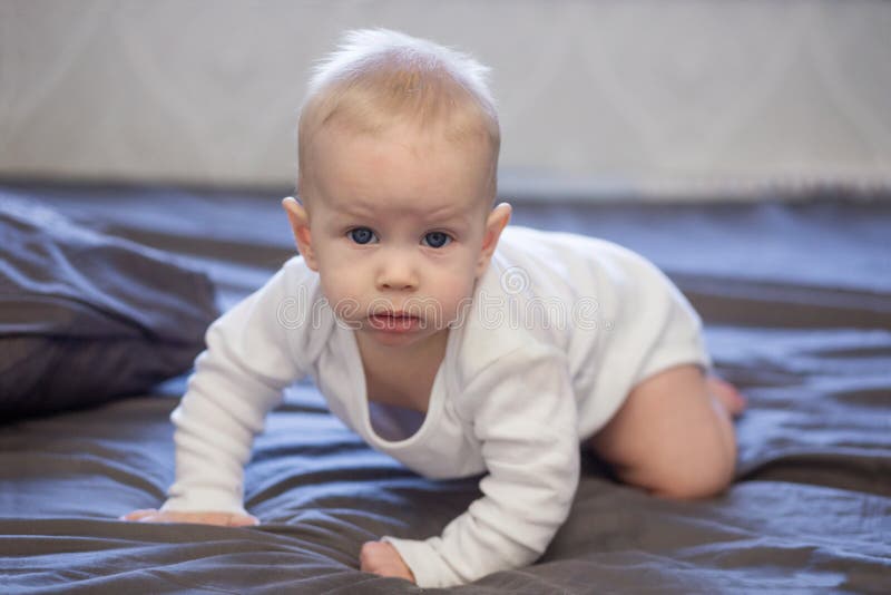Le bébé heureux rampe sur le lit images stock Le bébé heureux rampe sur le lit images stock