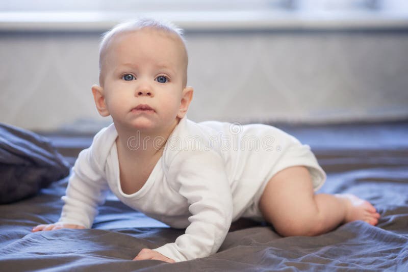 Le bébé heureux rampe sur le lit photos stock Le bébé heureux rampe sur le lit photos stock