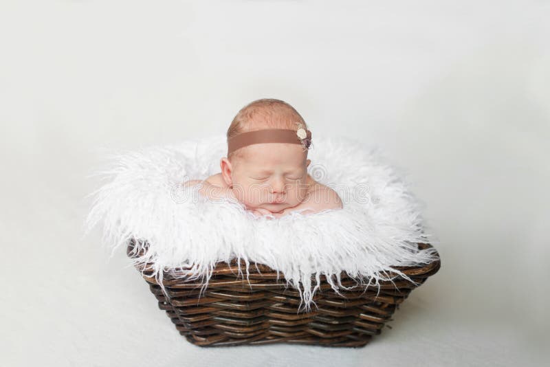 le bébé nouveau-né dort dans un panier brun sur un plaid blanc photo libre de droits le bébé nouveau-né dort dans un panier brun sur un plaid blanc photo libre de droits