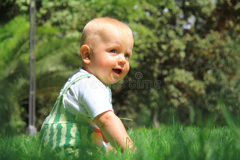 Le bébé s'assied sur une herbe images libres de droits Le bébé s'assied sur une herbe images libres de droits