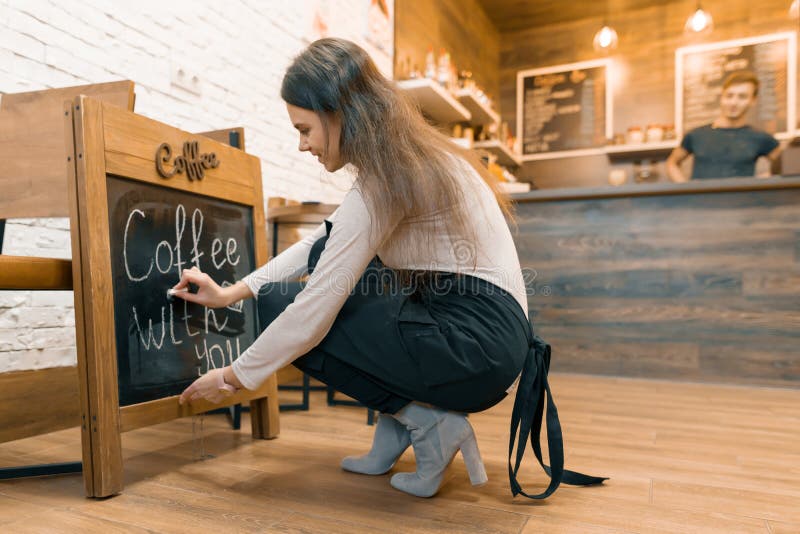 Le café avec vous, écrit dans la craie sur le tableau noir le jeune propriétaire féminin du café photo stock Le café avec vous, écrit dans la craie sur le tableau noir le jeune propriétaire féminin du café photo stock