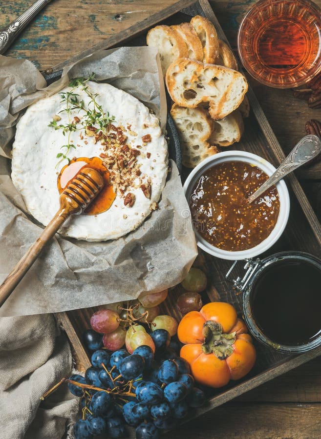 Le camembert, raisins, kaki, confiture de figue, miel, la baguette, verre de s'est levé photographie stock libre de droits Le camembert, raisins, kaki, confiture de figue, miel, la baguette, verre de s'est levé photographie stock libre de droits