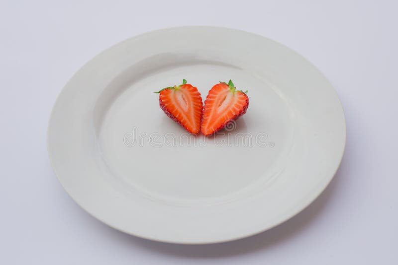 Le cerf fraise a formé, frais, organique divisée en deux et décorée d'un plat blanc photo libre de droits Le cerf fraise a formé, frais, organique divisée en deux et décorée d'un plat blanc photo libre de droits