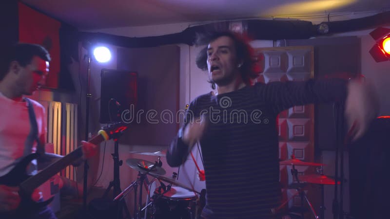 Le chanteur du groupe crie fort dans le microphone et se déplace au rythme clips vidéos