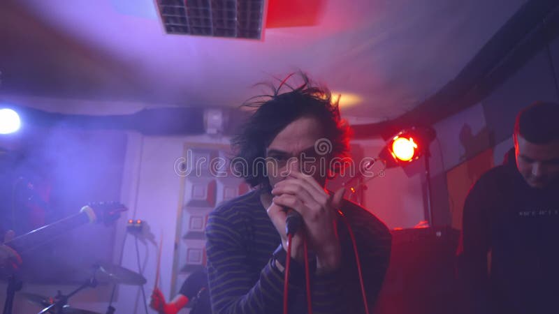 Le chanteur du groupe musical chante émotionnellement dans le microphone en fumée banque de vidéos