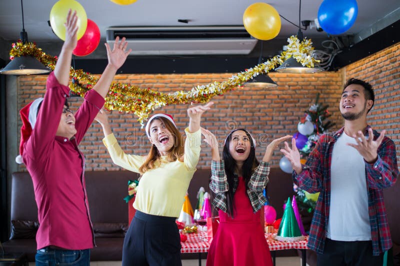 Le chapeau asiatique du père noël d'usage d'homme et de femme ayant l'amusement à la fête de Noël, danse et jouant monte en ballo photographie stock libre de droits Le chapeau asiatique du père noël d'usage d'homme et de femme ayant l'amusement à la fête de Noël, danse et jouant monte en ballo photographie stock libre de droits