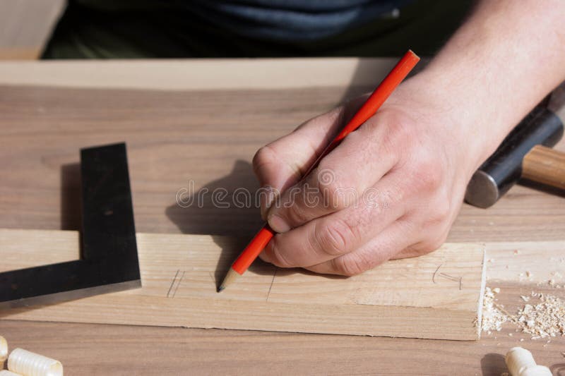 Le charpentier fait l'inscription de la partie en bois dans le crayon rouge images libres de droits