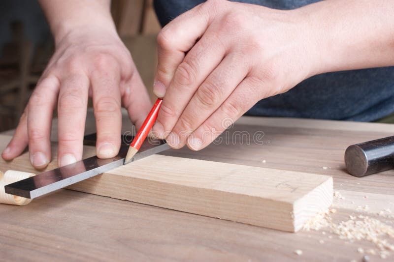 Le charpentier fait l'inscription de la partie en bois dans le crayon rouge photos stock