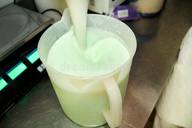 Le chef et le travailleur féminins travaille à l'usine de crème glacée, elle mélange le lait, l'extrait de menthe et la saveur se image stock Le chef et le travailleur féminins travaille à l'usine de crème glacée, elle mélange le lait, l'extrait de menthe et la saveur se image stock