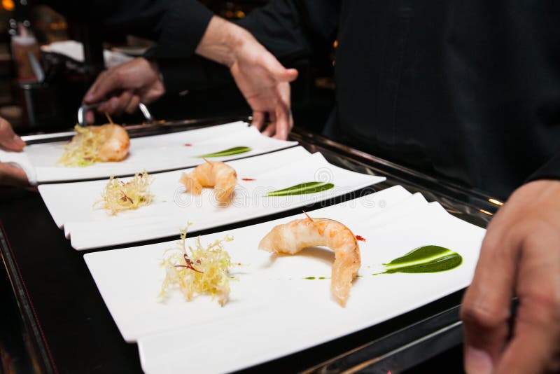 Le chef a mis la nourriture sur le plateau avant servi par le serveur image stock Le chef a mis la nourriture sur le plateau avant servi par le serveur image stock