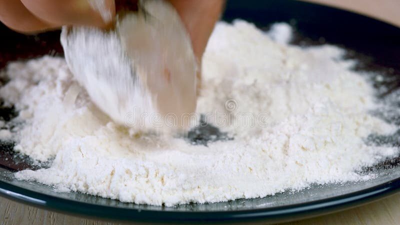 Le chef trempe des tranches de merlu ou de poisson de gobelet dans la farine dans l'assiette pour préparer un délicieux plat de po