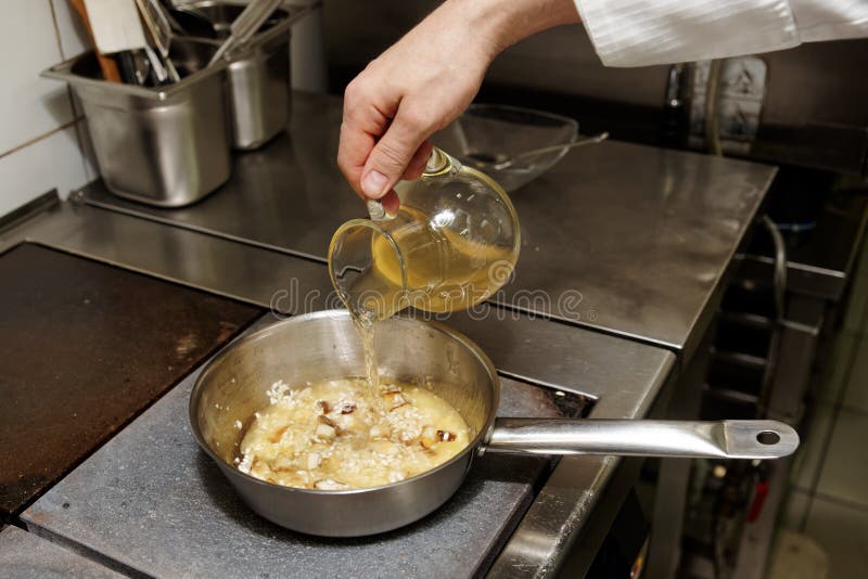 Le Chef Verse Le Bouillon Dans Une Cuvette Avec Le Risotto Photo stock