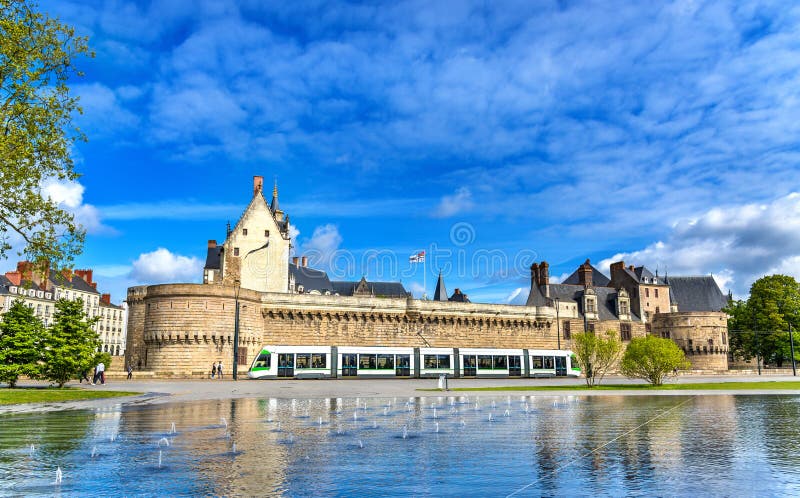 Le château des ducs de la Bretagne, un tram de ville et l'eau reflètent la fontaine à Nantes, France
