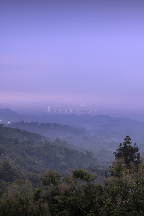Le ciel est d'une couleur violette profonde et les arbres sont couverts de brouillard. l'atmosphère brumeuse donne à la scène une ambiance paisible et sereine de punthuk setumbu hill magelang indonesia