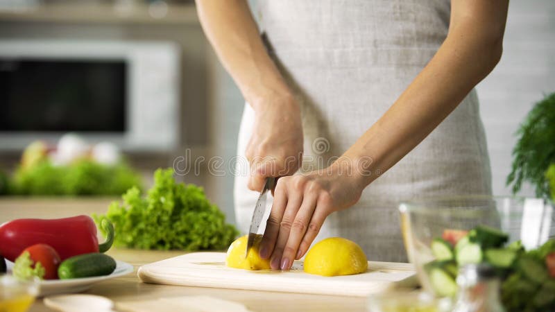 Le citron femelle de coupe de chef avec le couteau pointu pour le déjeuner préparant, faisant cuire incline image stock Le citron femelle de coupe de chef avec le couteau pointu pour le déjeuner préparant, faisant cuire incline image stock