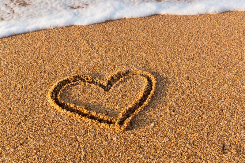 A heart is drawn on the sand on the beach during the day. Heart shape. Heart symbol. Love. Sea foam. A heart is drawn on the sand on the beach during the day. Heart shape. Heart symbol. Love. Sea foam.