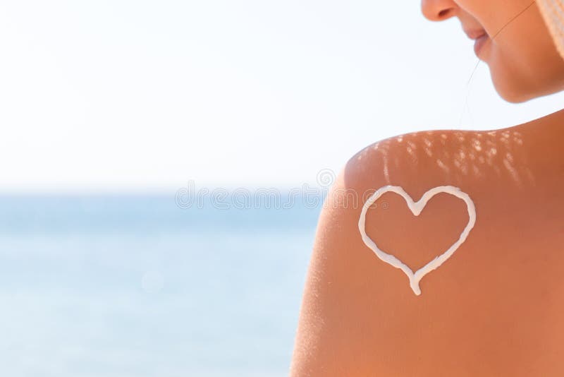 Le coeur fait de cr?me du soleil est dessin? sur l'?paule de la femme ? la plage images stock Le coeur fait de cr?me du soleil est dessin? sur l'?paule de la femme ? la plage images stock