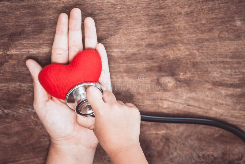 Le coeur rouge sur la main du ` s de femme et la fille de petit enfant examine photographie stock Le coeur rouge sur la main du ` s de femme et la fille de petit enfant examine photographie stock