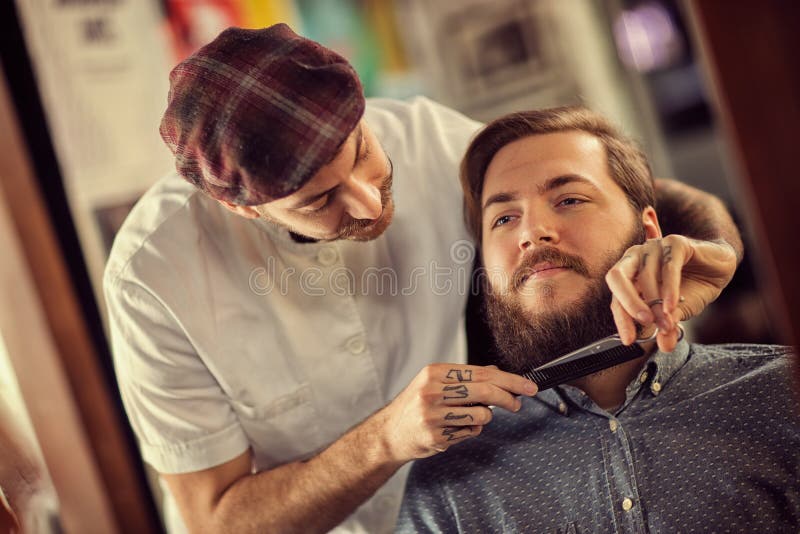 Le coiffeur avec le peigne noir et les ciseaux ont coupé la barbe images libres de droits Le coiffeur avec le peigne noir et les ciseaux ont coupé la barbe images libres de droits