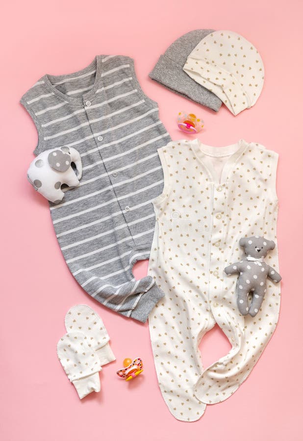 le concept de l'habillement du ` s d'enfants l'ensemble de ` blanc et gris s d'enfants vêtx sur un fond rose-clair Glisseurs, jou photo stock le concept de l'habillement du ` s d'enfants l'ensemble de ` blanc et gris s d'enfants vêtx sur un fond rose-clair Glisseurs, jou photo stock