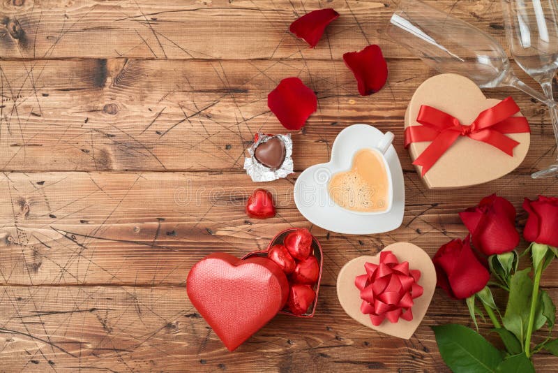 Le concept de Saint-Valentin avec la tasse de café, chocolat de forme de coeur, a monté des fleurs et des boîte-cadeau sur le fon photos libres de droits Le concept de Saint-Valentin avec la tasse de café, chocolat de forme de coeur, a monté des fleurs et des boîte-cadeau sur le fon photos libres de droits