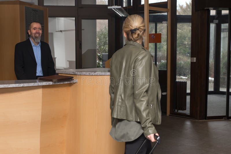 Le concierge dans un hôtel smilling à un invité féminin photo libre de droits Le concierge dans un hôtel smilling à un invité féminin photo libre de droits