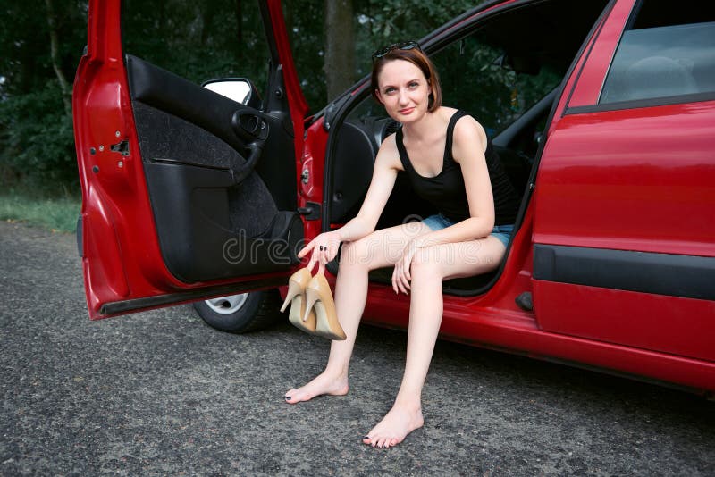 Le conducteur de jeune femme se reposant dans une voiture rouge, enlèvent leurs chaussures, concept heureux de voyage, femmes que photos libres de droits Le conducteur de jeune femme se reposant dans une voiture rouge, enlèvent leurs chaussures, concept heureux de voyage, femmes que photos libres de droits